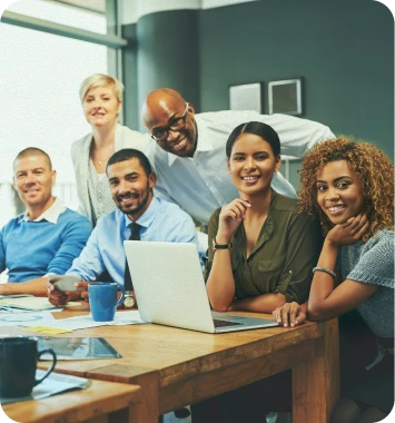 Equipe diversa reunida em torno de um notebook e trabalhando em conjunto